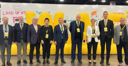 Fuarda “Land of Stone Turkey” yazılı sarı dev harflerin önünde yaka kartlı, yan yana poz veren bir grup