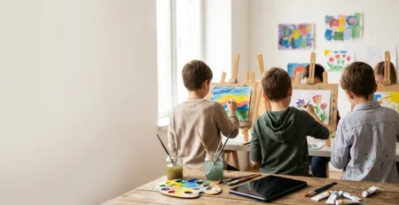 Resim kursunda şövale başında resim yapan çocuklar ve masada ters çevrilmiş bir tablet