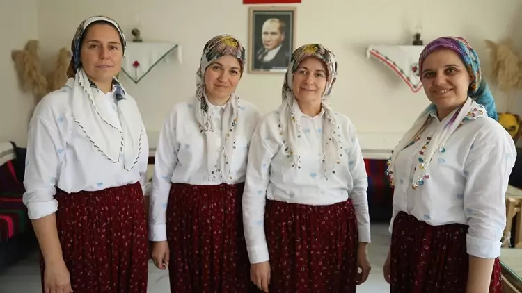Atatürk portresinin asılı olduğu odada, beyaz gömlek, bordo etek ve yemeni giyen dört kadın