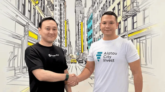 Şehir çizimli duvar önünde el sıkışan iki adam; birinin tişörtünde Alatau City Invest logosu