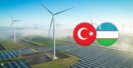 Rüzgâr türbinleri ve güneş paneli tarlası üzerinde Türkiye ve Özbekistan bayrakları