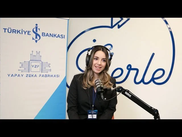 Türkiye İş Bankası ve Yapay Zekâ Fabrikası logolu fon önünde kulaklık takmış, mikrofon başında konuşan bir kadın