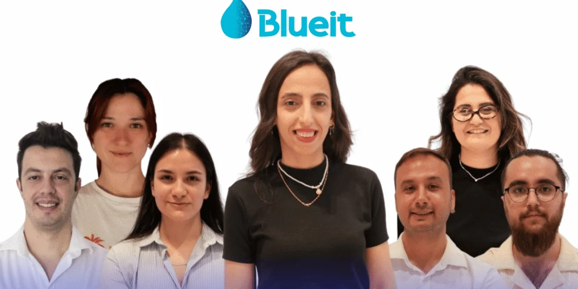 Blueit logosunun altında beyaz zemin önünde poz veren yedi kişilik ekip